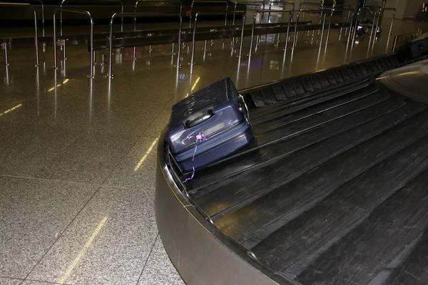 Uma mala está deitada em uma fita de bagagem na sala de chegada dos passageiros do aeroporto, o conceito de reclamação ou perda de bagagem — Fotografia de Stock