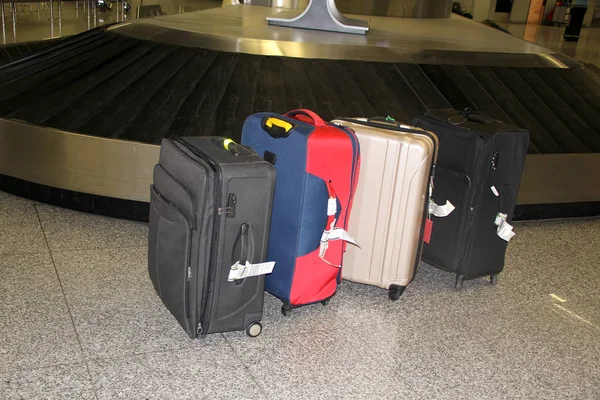 Muchas maletas de diferentes colores se encuentran en la sala del aeropuerto cerca del cinturón de equipaje, el concepto de pérdida de equipaje —  Fotos de Stock