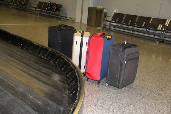 Muchas maletas de diferentes colores se encuentran en el salón del aeropuerto en el lado, cerca del cinturón de equipaje, el concepto de pérdida de equipaje —  Fotos de Stock