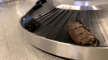 Bavullar havaalanındaki bagaj teslim odasında bir taşıma bandında yuvarlanıyor, seyahat konsepti.