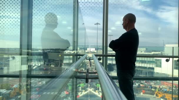 窓を待っている空港ラウンジの明るい建物の1人の男通りを見て旅行のコンセプト — ストック動画
