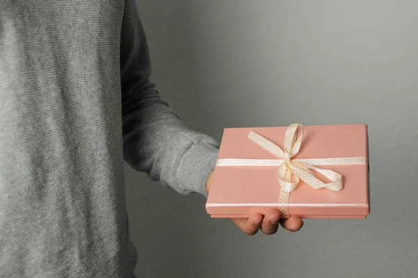 Homme tient un cadeau dans une boîte rose avec un ruban de satin à la main, concept de vacances — Photo