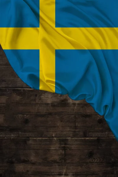 Vertikální barva národní vlajka moderního státu Švédsko, krásné hedvábí, pozadí staré dřevo, koncept cestovního ruchu, ekonomika, politika, emigrace, den nezávislosti, kopírovací prostor, šablona — Stock fotografie