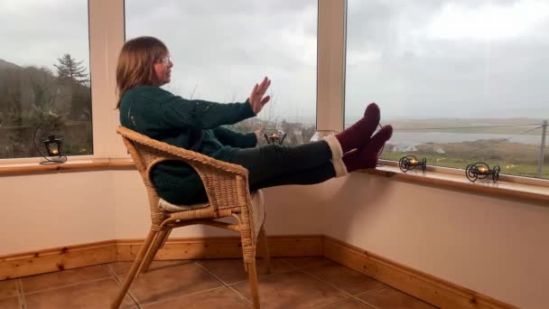 Mujer Sienta Una Acogedora Silla Mimbre Una Terraza Cerrada Luz — Vídeo de stock