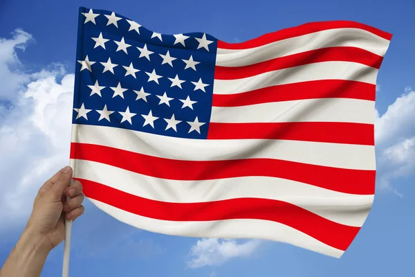 Male hand holds the national flag of the USA on a luxurious texture of satin, silk with waves, closeup, copy space — Stock Photo, Image