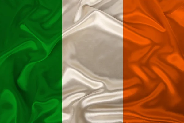 Photo of the national flag of Ireland on a luxurious texture of satin, silk with waves, folds and highlights, closeup, copy space, travel concept, economy and state policy, illustration — Stock Photo, Image