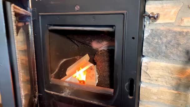 une flamme orange brûle dans un foyer sombre, clignotant et diffusant des étincelles 