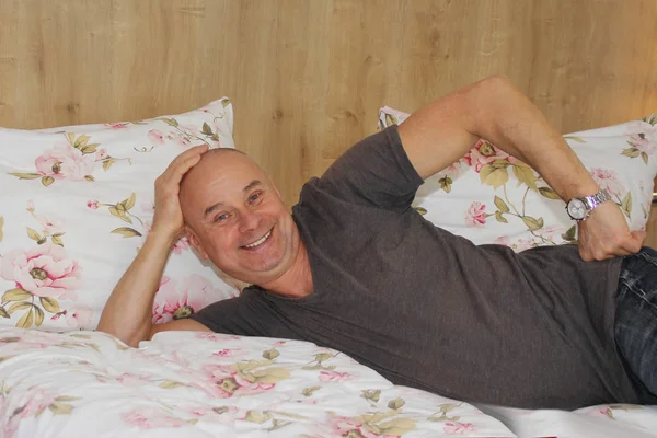Один веселый человек лежит улыбаясь на кровати в гостиничном номере, концепция отдыха, деловая поездка — стоковое фото