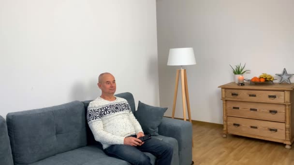 Ενήλικος Άνδρας Ένα Σκανδιναβικό Λευκό Πουλόβερ Κάθεται Έναν Καναπέ Και — Αρχείο Βίντεο