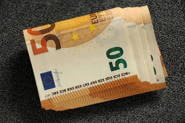 Stack of rolled up bills of the European Union currency of 50 euros on a gray fabric background, the concept of financial, devaluation, inflation, taxes — 스톡 사진