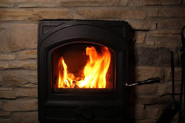 Bela chama vermelha de fogo de lenha em chamas em uma lareira preta de ferro, o conceito de uma casa acolhedora — Fotografia de Stock