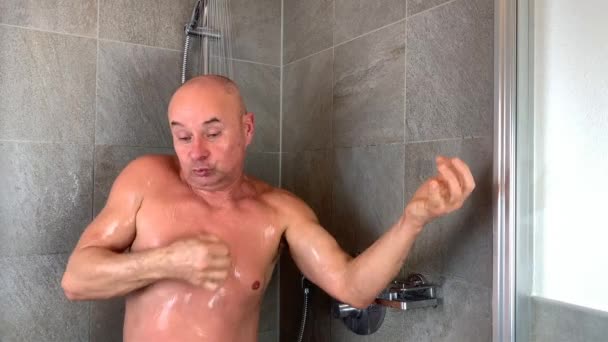 滑稽的秃头中年男子在淋浴间洗澡 并生动地描绘了他演奏乐器的情景 — 图库视频影像