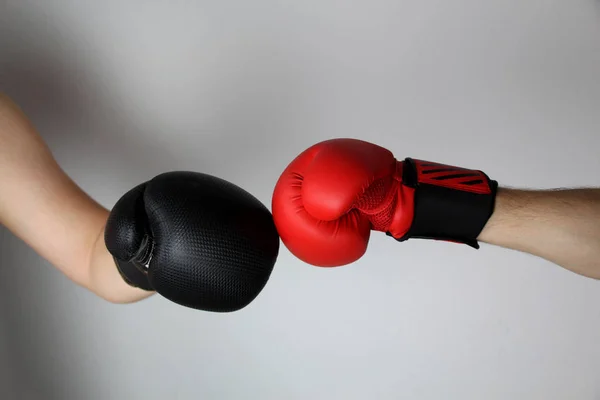 Manos de cerca de dos boxeadores en guantes de boxeo rojos y negros cerrados para el saludo deportivo sobre un fondo claro con espacio para texto de copia — Foto de Stock