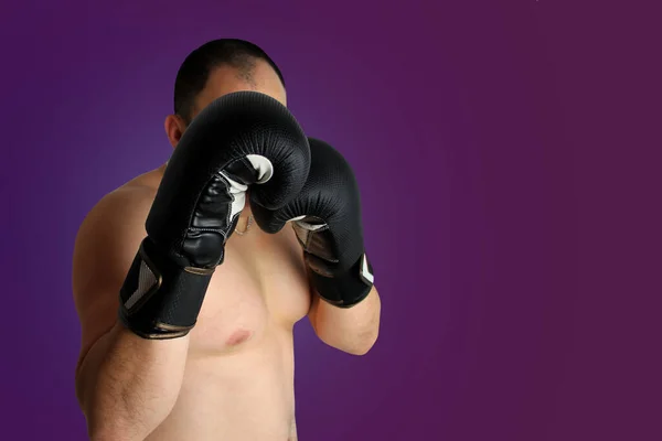 Primer plano de los boxeadores en guantes de boxeo negro en postura protectora sobre un fondo púrpura oscuro, espacio de copia —  Fotos de Stock