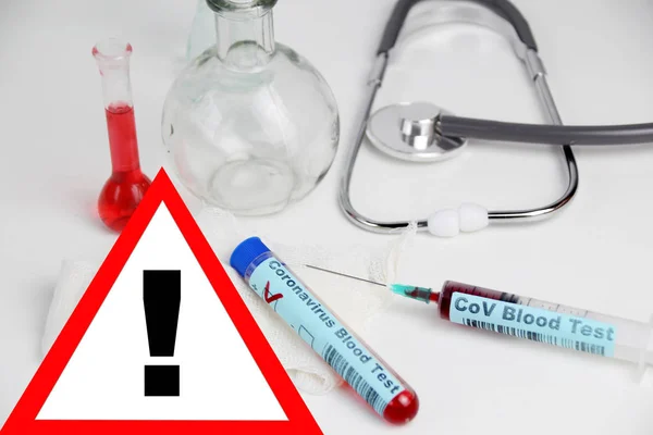 Medical laboratory test tube with the word coronavirus test and syringe with blood inside, stethoscope, flasks, danger concept of the spread of the CoV virus — Stock Photo, Image