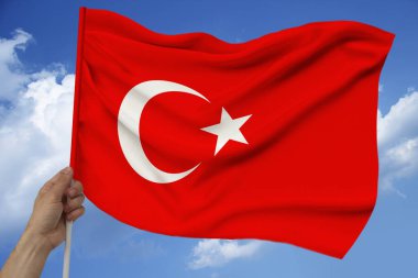 erkek el bulutları ile gökyüzünün arka planına karşı tutar Türkiye'nin ulusal bayrağı saten lüks bir doku, dalgalar ile ipek, closeup, kopya alan, seyahat kavramı, ekonomi, siyaset