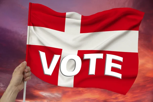 Mannelijke hand houdt de vlag van Denemarken op de achtergrond van de lucht met wolken een kleurrijke vlag van Denemarken op een luxe textuur van satijn, zijde met golven, closeup, kopieer ruimte — Stockfoto