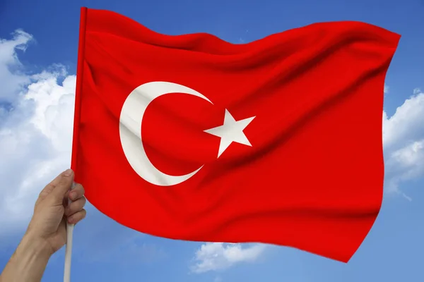 Erkek el bulutları ile gökyüzünün arka planına karşı tutar Türkiye'nin ulusal bayrağı saten lüks bir doku, dalgalar ile ipek, closeup, kopya alan, seyahat kavramı, ekonomi, siyaset — Stok fotoğraf