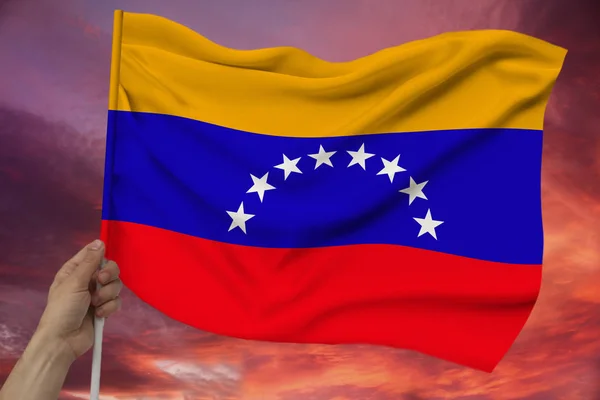 Чоловіча рука тримає на тлі неба з хмарами Національний прапор Венесуели на розкішна текстура атласу, шовк з хвилями, крупним планом, копіювати простір, концепція подорожей, економіка, політика — стокове фото