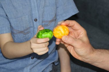 Çocuk elinde bir yeşil yumurta tutuyor, yetişkin sarıya sahip, Paskalya eğlencesi konsepti