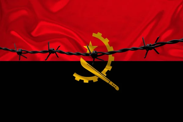 Iron barbed wire against the background of the national silk flag of the state of Angola, concept of imprisonment for offenders, for the siege area — Stock Photo, Image