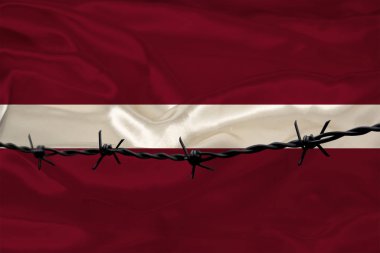 Letonya devletinin ulusal ipek bayrağının arka planında demir dikenli tel var. Suçlular için, kuşatma bölgesi için konsept hapis.