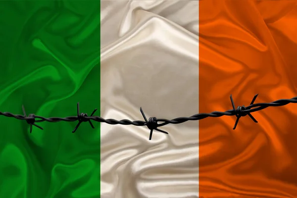 Alambre de púas de hierro en el contexto de la bandera nacional de seda del Estado de Irlanda, el concepto de encarcelamiento para los delincuentes, para la zona de asedio — Foto de Stock