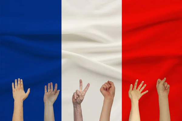 Многие поднятые руки людей на фоне цветного шелкового государственного флага с мягкими складками, люди концепции единства — стоковое фото