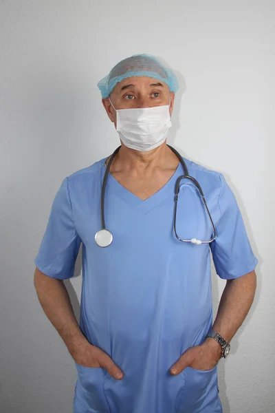 Man läkare i blå uniform med ett stetoskop i en skyddande mask — Stockfoto
