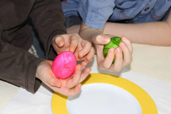 子供は手に1個の緑の卵を持ちもう1個はピンクの卵を持っていますイースター・ファンの概念です — ストック写真
