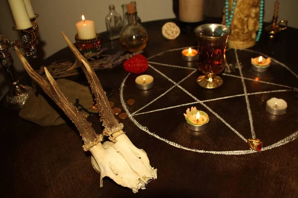 Candles are lit in a dark room on a round table, in silver candelabra, animal skulls lie, a pentagram is drawn, a concept of magic and witchcraft — Stock Photo, Image