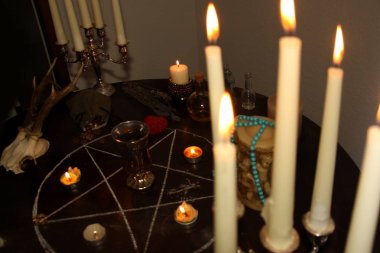 Mumlar yuvarlak bir masanın karanlık bir odasında, gümüş şamdanlarda, falcılık kartları seriliyor, bir pentagram çiziliyor, bir sihir ve büyücülük konsepti.