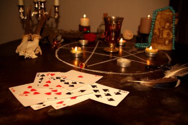 Mumlar yuvarlak bir masanın karanlık bir odasında, gümüş şamdanlarda, falcılık kartları seriliyor, bir pentagram çiziliyor, bir sihir ve büyücülük konsepti.