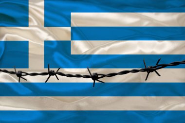 Yunanistan devletinin ulusal ipek bayrağının arka planına demir dikenli teller geriliyor. Suçlular için kuşatma bölgesi için hapis kavramı.