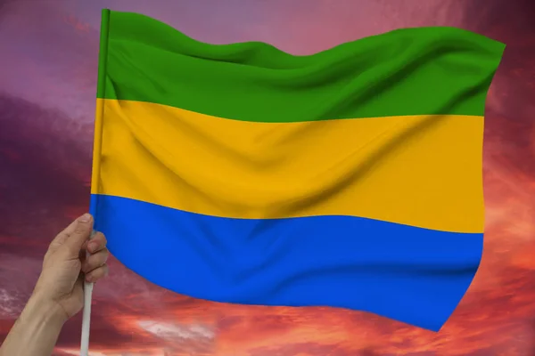 El bulutlar ile gökyüzünün arka planına karşı kumaş dokusunda Gabon renk bayrağı tutar, dalgalar ile ipek, yakın çekim — Stok fotoğraf