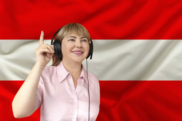 Жінка в навушниках на тлі національного прапора Австрії на тендітний блискучий шовк, концепція вільного мовлення, музика, новини, подкаст, горизонтальний, зблизька, копіювальний простір. — стокове фото