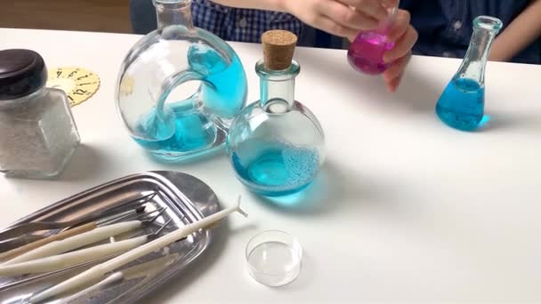 子供たち小学生の男の子がガラスのフラスコに色のついた液体を注ぎピペットと注射器から滴り落ちる幼児教育の概念 4Kスローモーション撮影 — ストック動画