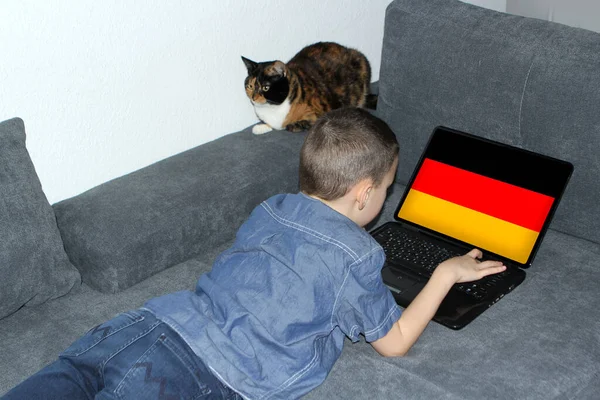 Niemiecka Flaga Wyświetlaczu Laptopa Mały Uczeń Dżinsach Leży Kanapie Zwojach — Zdjęcie stockowe
