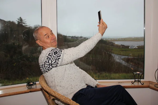 Beyaz Kazaklı Neşeli Bir Adam Verandanın Geniş Penceresinde Oturup Kendini — Stok fotoğraf