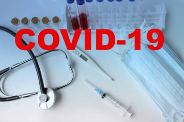İçinde kan olan tıbbi laboratuvar tüpü, stetoskop, şırınga, koruyucu maskeler, Coronavirus Covid-19 virüsünün yayılma tehlikesi kavramı.