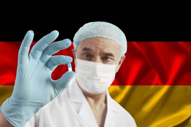 Bir eczacının elinde ilaç olan beyaz, mavi kapsül, Almanya 'nın güzel ipek bayrağının arka planına karşı doktor, hastalıklar için bir panasya kavramı, tedavi