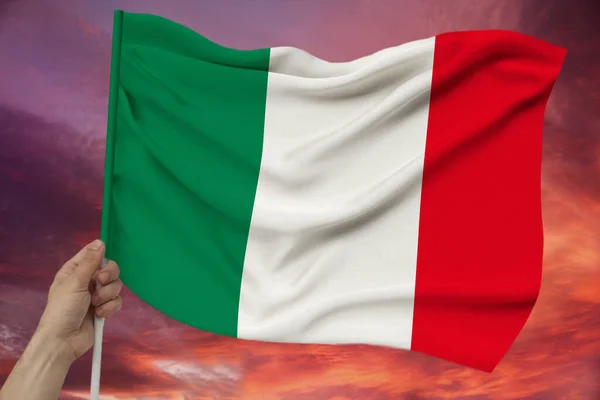 手拿着天空的背景与云的意大利彩色国旗的面料纹理 丝绸与波浪 — 图库照片