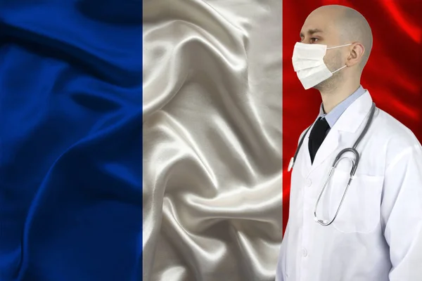 doctor with a stethoscope on the background of the silk national flag of France, concept of national medical care, health, insurance and tourism