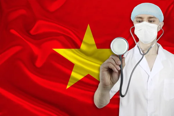 male doctor with a stethoscope on the background of the Vietnam silk national flag, concept of national medical care, health, insurance, tourism
