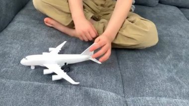 Siyah gözlüklü çocuk beyaz bir uçak oyuncağıyla oynuyor, uçuş konsepti, seyahat