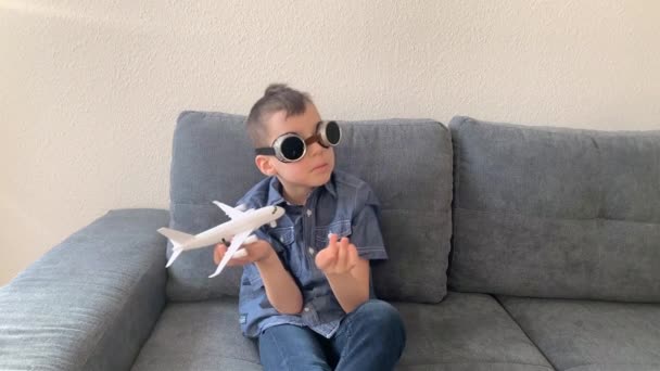 黒い眼鏡の子供は白い飛行機のおもちゃ 飛行の概念 旅行で遊ぶ — ストック動画