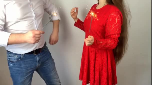 穿着白衬衫的年轻人和穿着漂亮红色衣服的女孩正在举行点燃的火花 这是个度假的概念 一个浪漫的约会 — 图库视频影像