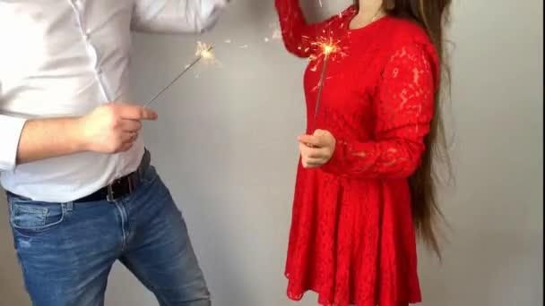 白いシャツを着た若い男と赤いドレスを着た女の子が輝くライトを持っている休日の概念ロマンチックなデート — ストック動画