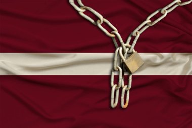 Demir zincir ve kilit, Letonya 'nın ipek ulusal bayrağında güzel kıvrımlar, turizm, siyasi baskı, suç, vatandaşların hak ve özgürlüklerinin ihlali konsepti