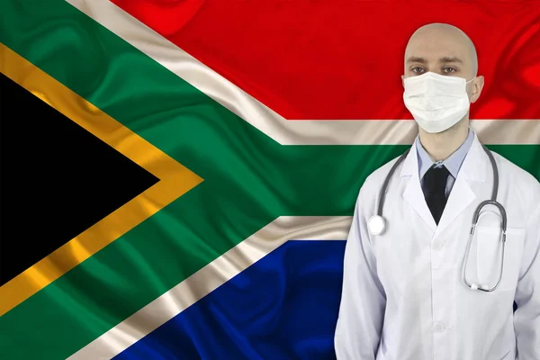 male doctor with a stethoscope on the background of the silk national flag of South Africa, the concept of national medical care, health, insurance, tourism